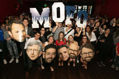 Crowd shot of various people holding "MoFo" signs. 